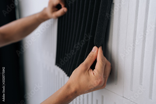 Foto Close-up cropped shot of handyman installing acoustic foam panels onto a soundproof wall, enhancing noise reduction and sound absorption for a recording studio or home theater environment