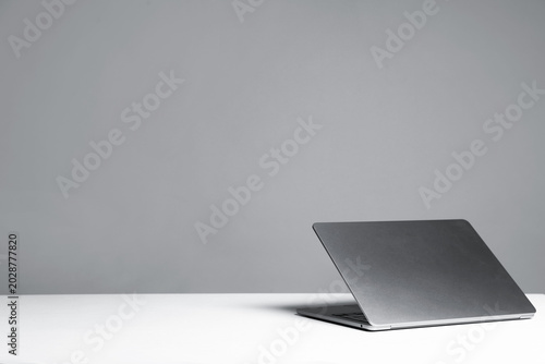 Stylish workplace. Modern laptop on white table against gray background. Space for text
