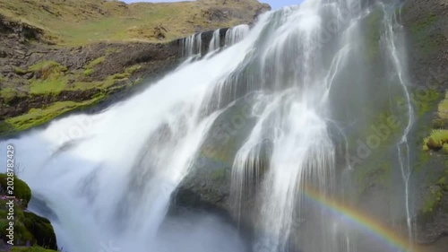 Majestic waterfall cascading over cliffs with lush greenery and rainbow  