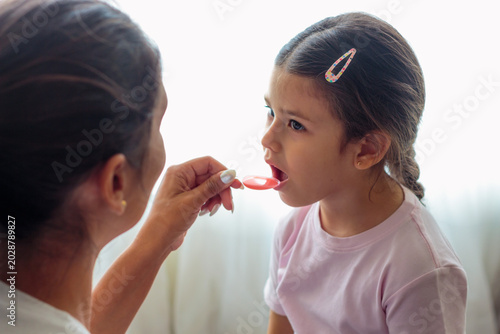 Schilderij op canvas Niña tomando jarabe pediátrico con cuchara medidora