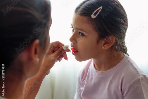 Fotografie Niña tomando jarabe pediátrico con cuchara medidora
