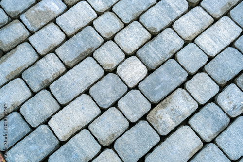 Cuadro en lienzo Closeup of gray cobblestone pavement laid in diagonal pattern, textured stone bl
