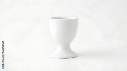 Minimalist white ceramic egg cup standing alone on a clean bright background for elegant kitchen tableware and breakfast dining