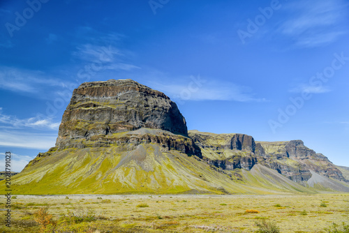 Isolated cliff rising from black volcanic plain