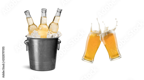 Group of light beer bottles chilling in an old metallic ice bucket alongside two clinking glasses of foamy golden beer splashing with white background, clinking