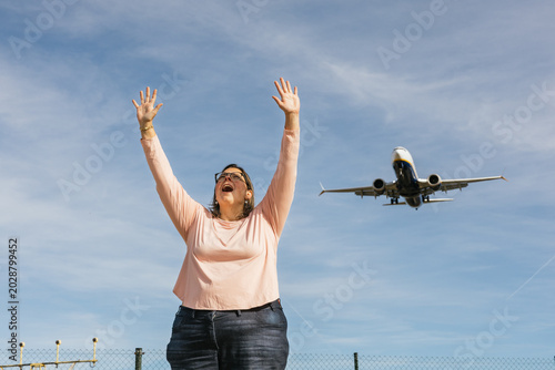 Woman celebrating joyful arrival watching airplane landing