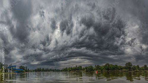 Tableau sur toile Dark shelf cloud above lake with dramatic storm atmosphere
Massive layered storm cloud reflected above calm water creating intense weather landscape scenery
