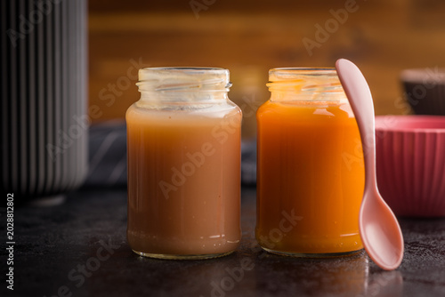 Homemade Baby Food Carrot Puree in Glass Jars with Bowl and Spoon on Dark Surface