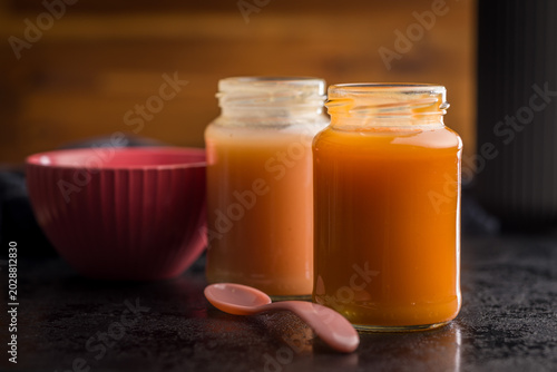Homemade Baby Food Carrot Puree in Glass Jars with Bowl and Spoon on Dark Surface