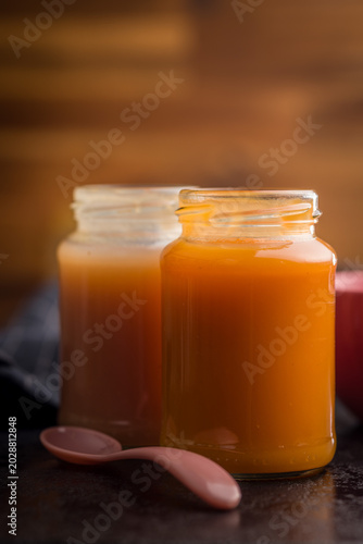Homemade Baby Food Carrot Puree in Glass Jars with Bowl and Spoon on Dark Surface