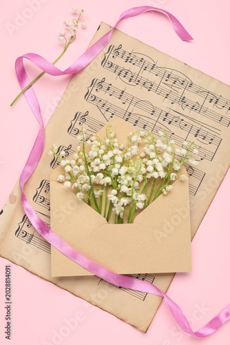 Kraft envelope with fresh lily-of-the-valley flowers, sheet with musical note...