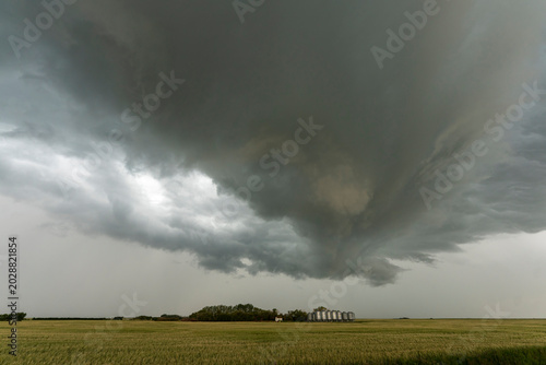 Dramatic shelf cloud looms over a rural landscape with grain silos
