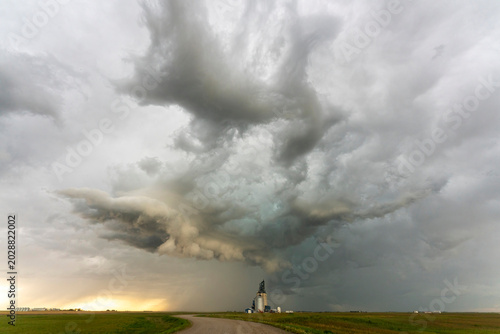 Dramatic storm clouds gather over a rural landscape with grain elevators