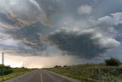 Stormy sky over a lonely highway in the countryside with rain falling in distance