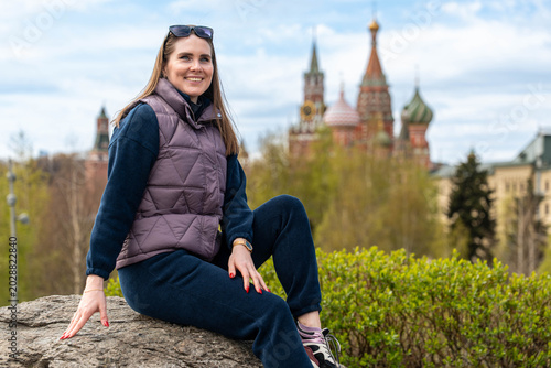 Canvas Print Young Woman Sitting On Rock Smiling At Camera Wearing Vest And Sunglasses St Bas