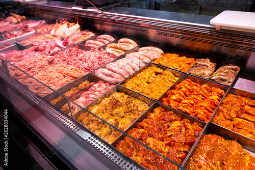 Supermarket meat counter with marinated barbecue meat, shashlik, lula kebab, grill sausages, and minced meat ready for cooking.