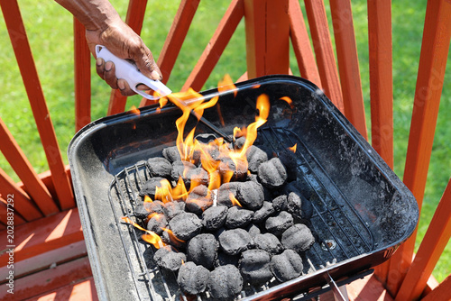 A black man lighting a charcoal grill