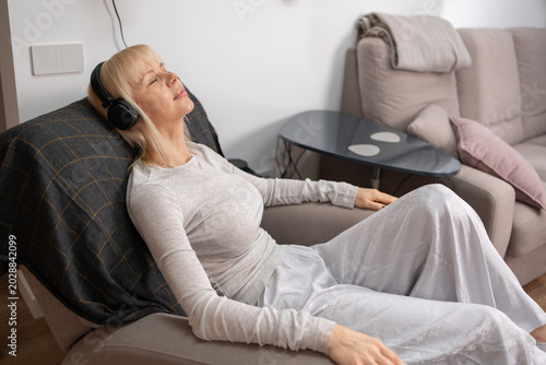 Sound Relaxation. Female resting in chair wearing black headphones enjoying music at home quiet domestic atmosphere comfort moment.