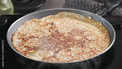 cook remove freshly baked crepe from hot frying pan with spatula in kitchen. process of making delicious pancakes at home for healthy breakfast, food close up