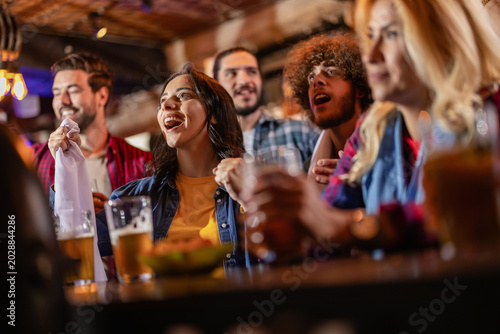 Konstfotografi Concentrated friends leaning on a bar counter and waiting for a soccer goal at a pub