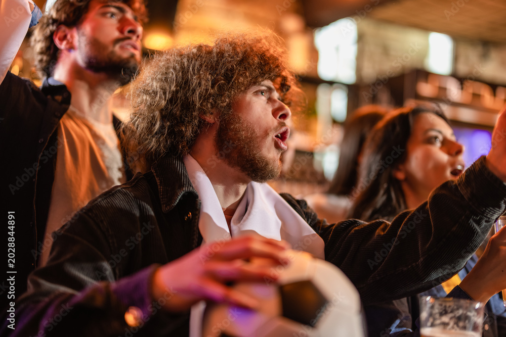 Fototapeta premium Furious sports fan shouting at a television screen in frustration over a lost match.