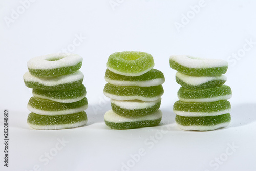 Three separate vertical stacks of green and white gummy loop candies arranged neatly on a clean white background