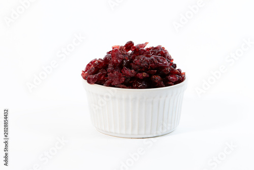 A white ceramic cup filled with dried cranberries isolated on a clean white background