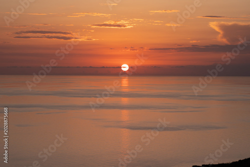 Epic Mediterranean sea sunset panorama. 
Cinematic ground view of golden sun 
setting down over calm ocean horizon.
