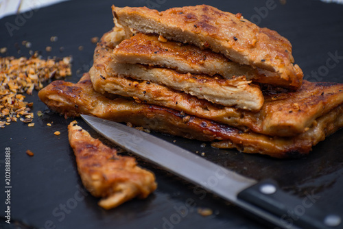 Vegan seitan schnitzel slices on slate plate, cut steak style