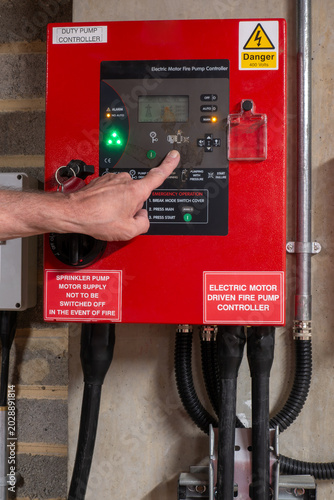 Specialist sprinkler service engineer resetting pump controller alarm after servicing and running the sprinkler pump sets. Service engineer resetting a sprinkler system after a compliance check.