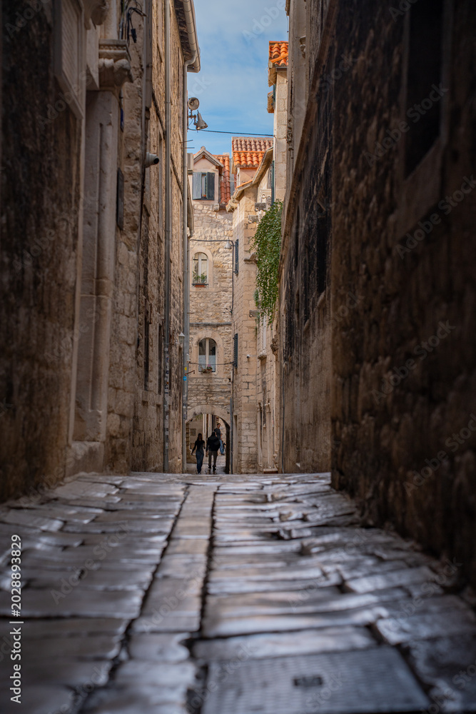 Obraz premium Epic traditional old town narrow street ancient architecture vertical panorama. Cinematic view of historic medieval limestone house facades, wooden window shutters, vintage iron lantern and cozy all