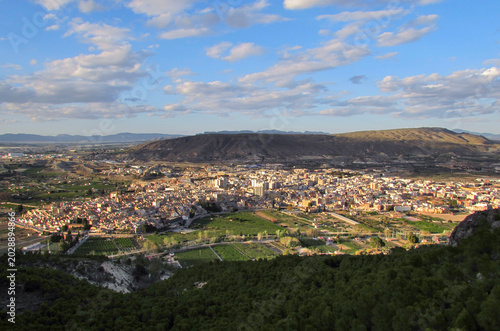 High-angle panoramic view of the city of Cieza surrounded by agricultural fields and arid mountains.
