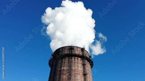 Industrial smokestack billowing white smoke against vibrant blue sky pollution environment concept