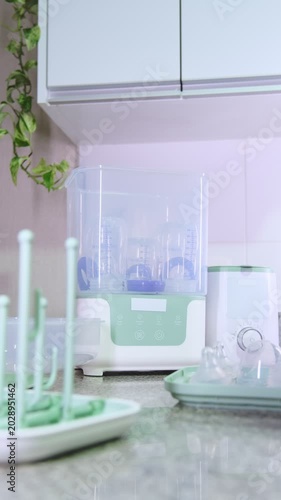 Man placing baby bottle nipples, pacifiers, and bottles into a sterilizer and turning it on