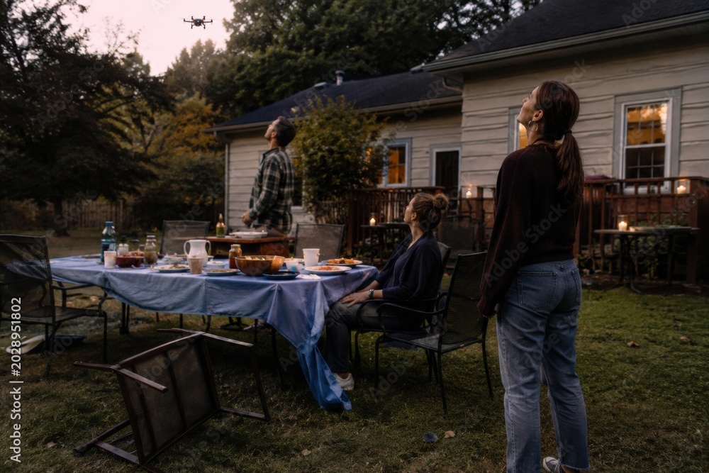 Fototapeta premium Group of friends enjoying outdoor dinner party at backyard during sunset