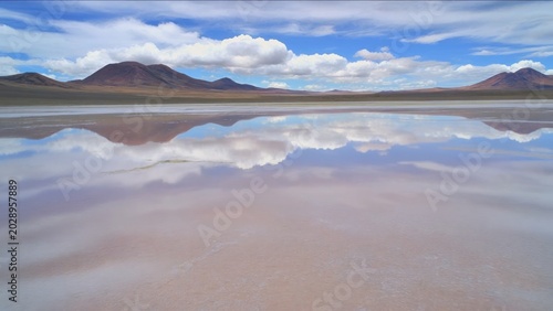 Serene Mountain Landscape Reflected in Shallow Salt Flat Under Cloudy Blue Sky