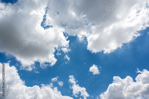 Bright Blue Sky with Fluffy White Clouds and Sunlight Peeking Through