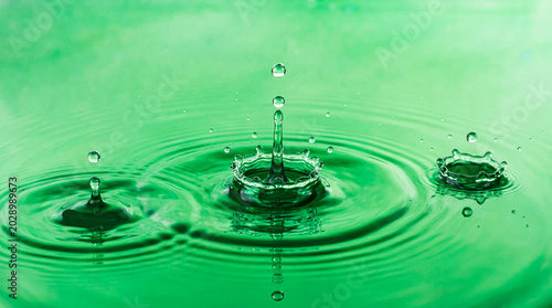 Fotografía Close-up photograph of several water drops creating ripples and splashes on a vibrant green liquid surface