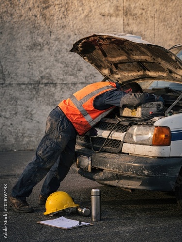 Exhausted worker in a safety vest slumped over a van hood for contractor wellbeing, labor rights editorial and facility management burnout advertising with copy space