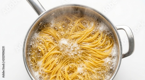 Top down view of spaghetti noodles cooking in bubbling water in a metal saucepan.