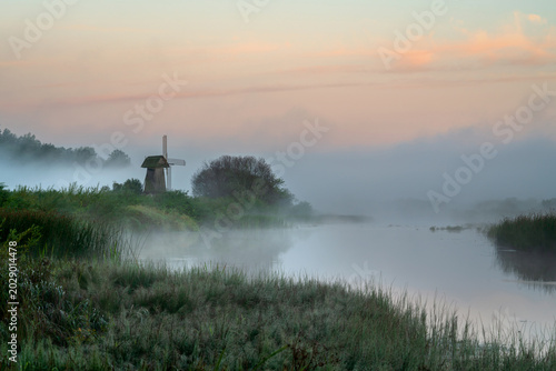 фотографія An ancient wooden windmill on the banks of the Sorot River on a foggy summer mor