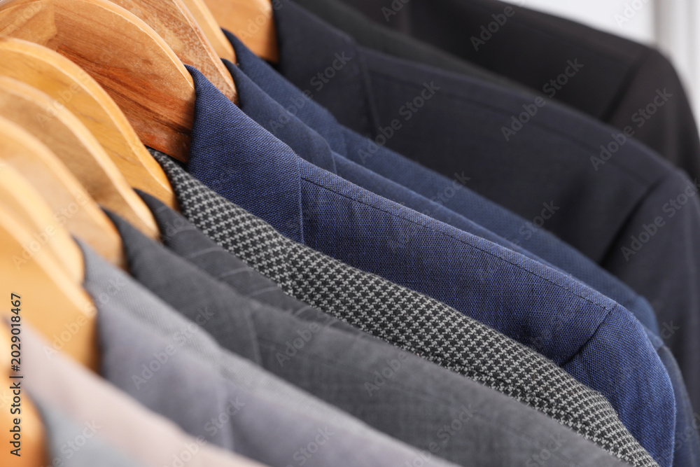 Obraz premium Rack with different stylish male suits in dressing room, closeup