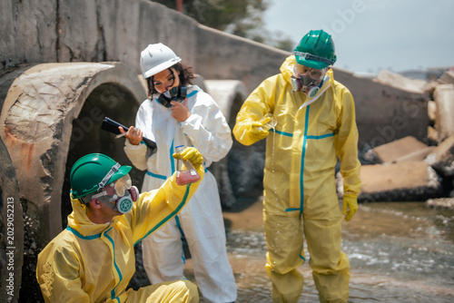 фотографія Scientists collecting polluted liquid samples from contaminated drainage canal to evaluate industrial wastewater toxicity and environmental damage in coastal ecosystem area