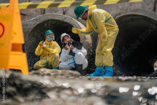Quadro em tela Industrial pollution investigators testing contaminated wastewater in coastal runoff channel while documenting environmental hazards and performing scientific field research activities