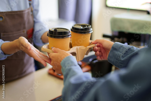 barista serving takeaway coffee drinks to customer hands holding paper cup tray cafe counter small business service hospitality food beverage industry worker
