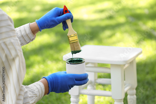 Woman painting white stool ...