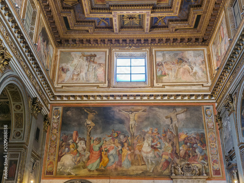 Large crucifixion fresco and ornate coffered ceiling inside San Marcello al Corso church, Rome, Italy
