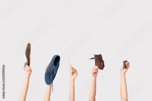 Fotografie Female hands with shoe pieces, awl and sewing thread on white background