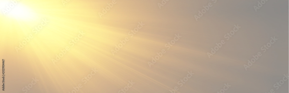 Obraz premium Warm morning sunshine spreading bright diagonal light rays across a hazy sky