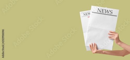 Foto Hand holding two newspapers with 'NEWS' headlines on light green background